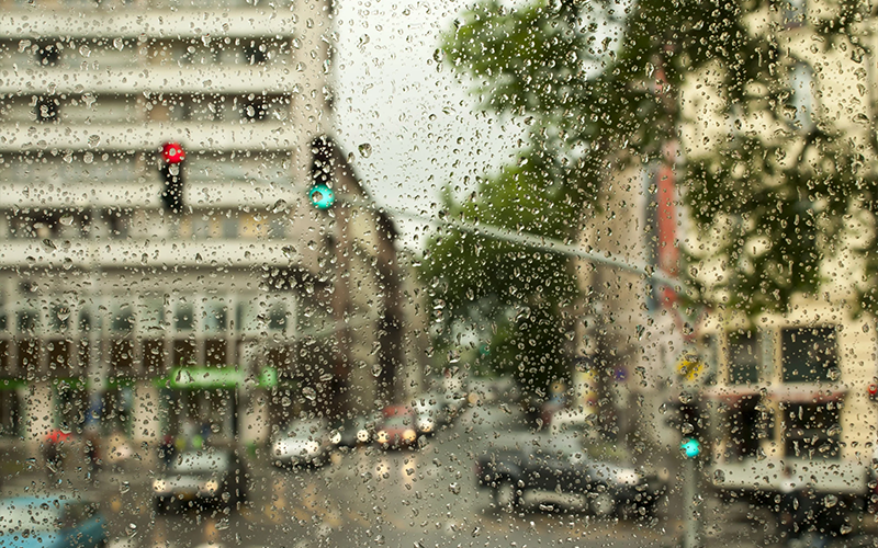 edificios-por-la-carretera-vistos-traves-de-una-ventana-humeda-durante-el-monzon-scaled