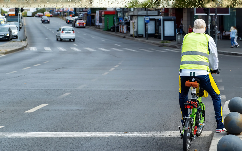 hombre-en-la-carretera-en-una-pequena-bicicleta-verde-calle-con-coches-y-personas-scaled (1)
